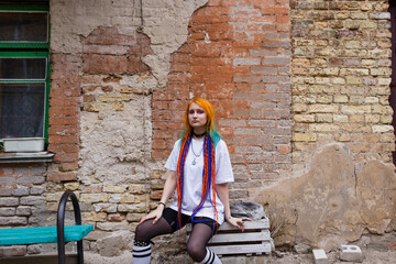 Portrait of a young tattooed punk girl with long dyed hair. A girl with long colored hair is standing on the street . Stylish modern youth