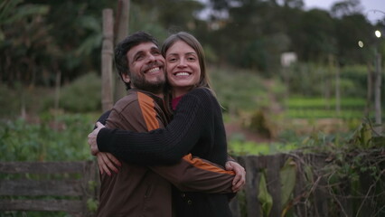 Fototapeta premium Couple in 30s embrace standing outdoors at dusk evening wearing sweaters during cold night. Friends hugging each other