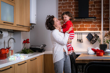 Portrait Christmas mother and little curly girl dancing on decorated xmas kitchen at home, preparing Christmas holidays , New Year family.