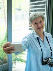 Portrait of happy senior adult elderly asia woman 60s taking selfie photo using smartphone camera...