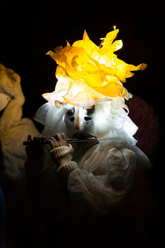 Switzerland, Basel, 7 March 2022. Closeup of a single carnival participant wearing an illuminated white costume and playing piccolo.