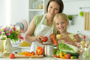 Beautiful girl with her mother preparing a salad in the kitchen