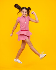 Happy teenager, positive and smiling emotions of teen girl. Full size photo of positive teen girl jump with movement summer dress, fashion kids outfit isolated over yellow background.