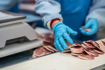Mid section of butchers cutting meat and checking the weight of meat at meat factory.