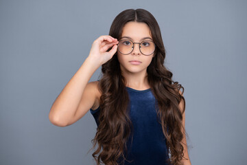 Teenager child wearing glasses on gray studio background. Cute girl in eyeglasses.