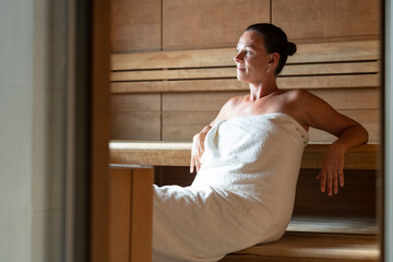 Senior woman sitting relaxed in a wooden sauna