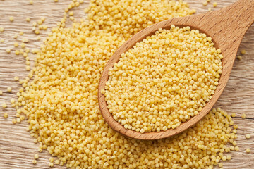 pile of sorghum or sorghum grain, millet grain or millet seed in wood spoon on wooden table background                                                   