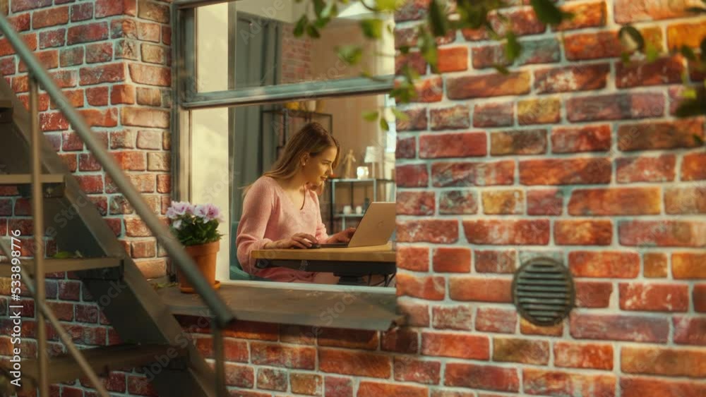 Poster portrait of a young female student using laptop computer while sitting behind a table in her stylish