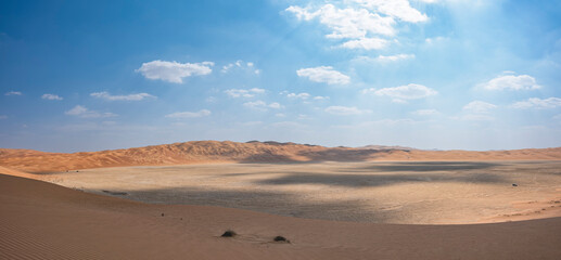 Fototapeta na wymiar Off-road vehicles driving thru a continental sabkha between high sand dunes in the Abu Dhabi Emirates, United Arab Emirates, Middle East