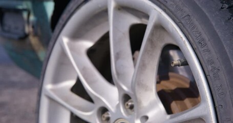 Person hand takes out car pump hose nozzle after pumping wheel tire for driving. Driver makes sure about quality of inflated tires for drifting