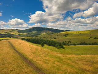 Beautiful white clouds are flowing across the sky over the green Zlatibor hills landscape on sunny summer day
