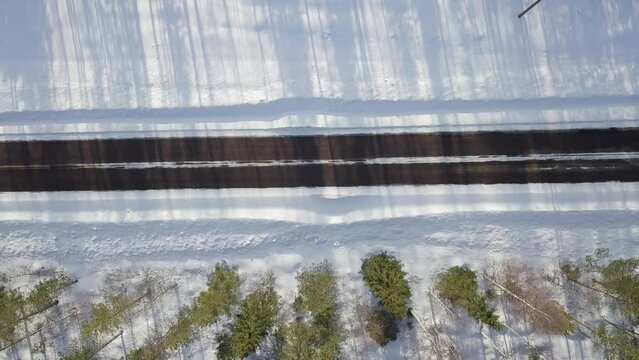 Winter icy road conditions in Finnish Lapland. Drone flying slowly left to right and camera is straight down. Black car and white van driving in same way over image area.