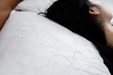 closeup hair loss fallen on pillow with blur background of woman sleeping in bed