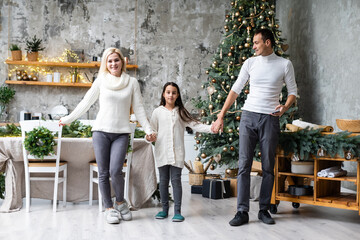 Merry Christmas and happy Holidays. Mom, dad and daughter decorating christmas tree.