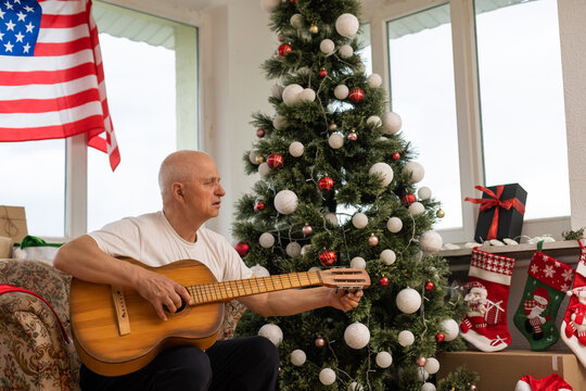 man holding guitar in front American Flag haning behind him at christmas