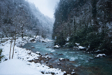 turquoise mountain river snow-capped mountains during a snowfall