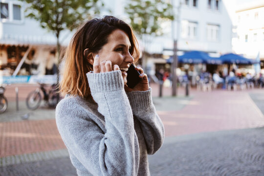 Young happy woman talking on cell phone downtown