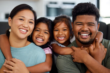 Family, smile and love of children for their mom and dad while sitting together in the lounge at home sharing a special bond. Portrait of happy Filipino man, woman and girl kids hugging their parents