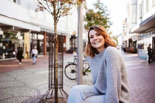 Laughing young woman in downtown looks at camera