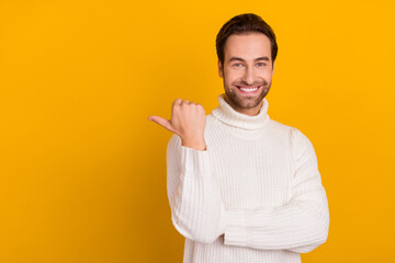 Photo of cheerful handsome guy indicate thumb empty space wear white sweater isolated yellow color background