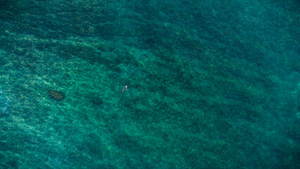 Surfer moves to the best waves on the crystal clear water of the ocean.