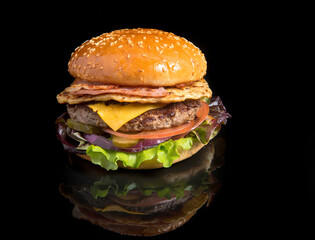 juicy burger with beef, cheese, tomato and green salad on a black background with reflection