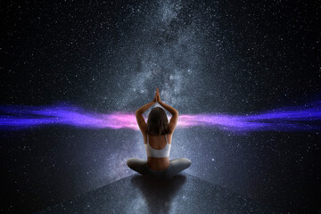 Young girl practicing yoga and meditating in front of the universe