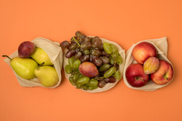 Reusable Grocery Bags With Fruits Reusable Packaging for Fruits and Vegetables Zero Waste Concept Orange Background Top View Harvest Concept