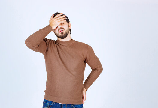 Portrait of a young man with face palm gesture on white background