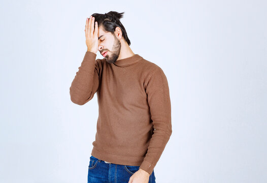 Portrait of a young man with face palm gesture on white background