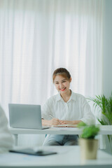 Beautiful Asian woman smiling happily relaxing using laptop computer in office. creative young girl working and typing on keyboard online work concept vertical picture