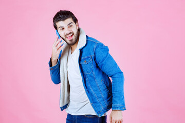 Young man wearing a blue jacket and white t-shirt standing against a pink background, casual fashion, modern style