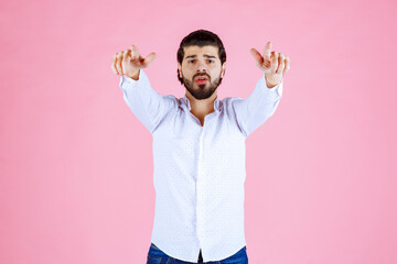 Child in a white shirt making a peace sign gesture against a pink background