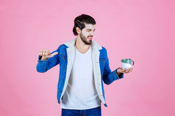 Child Holding a small container and spoon against a pink background, engaging in a playful activity or snack time, dressed in a blue jacket and white shirt