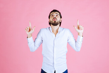 Person with blurred face wearing a white shirt making peace signs against a pink background