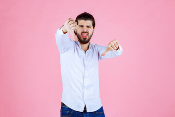 Young man in a light blue shirt posing with fists raised against a pink background, conveying confidence and energy