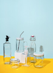 Glass containers and water bottles lie on a yellow and mint background