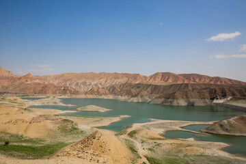 View of a mountain valley with a Azat river reservoir with a bright turquoise color in Armenia and arid terrain in the background.