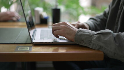 Young entrepreneur opening laptop and using modern technology inside seated at coffee shop table
