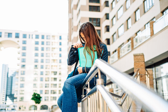 Back to school student teenager girl with a textbook. Outdoor portrait of young teenager brunette girl with long hair. girl on city