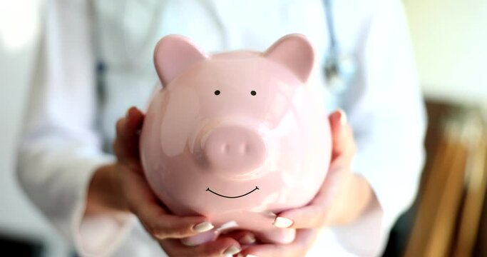 Doctor holding pink piggy bank closeup 4k movie slow motion 