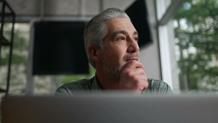 Thoughtful older executive staring out window. Pensive middle aged person contemplating decision. Senior businessman in meditation