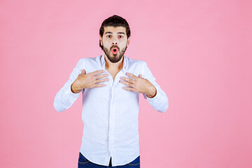 Young man adjusting his white shirt against a pink background, casual style, confident pose, modern fashion, vibrant color contrast