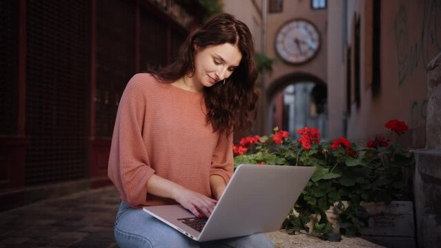 Attractive young woman using laptop on decorative stone of city streets, Pretty student preparing for classes in nature, and an adult lady studying outdoors