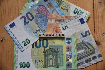 Das Wort Wohngeld mit Holzbuchstaben auf liegenden Euroscheinen
