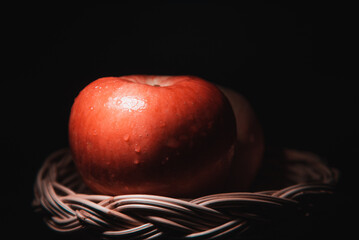 fresh red apples in the basket On a black background with water droplets, lights are falling with...