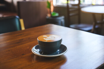 Closeup image of a cup of hot latte coffee with latte art on wooden table in cafe