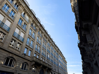 Low angle view of luxury French haussmannian apartment building with clear blue sky above the street