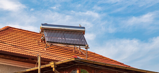 Solar water heater installed on tile roof of house for eco heating of water. Large water tank....