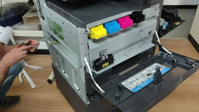 Technician repairing a color copier on the floor
